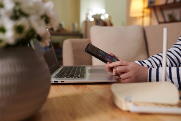 Man using mobile while sitting beside the router and laptop