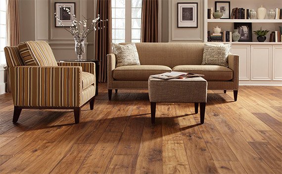 A stylish living room featuring rich, dark hardwood flooring with a comfortable seating area, showcasing elegant furniture and natural lighting.